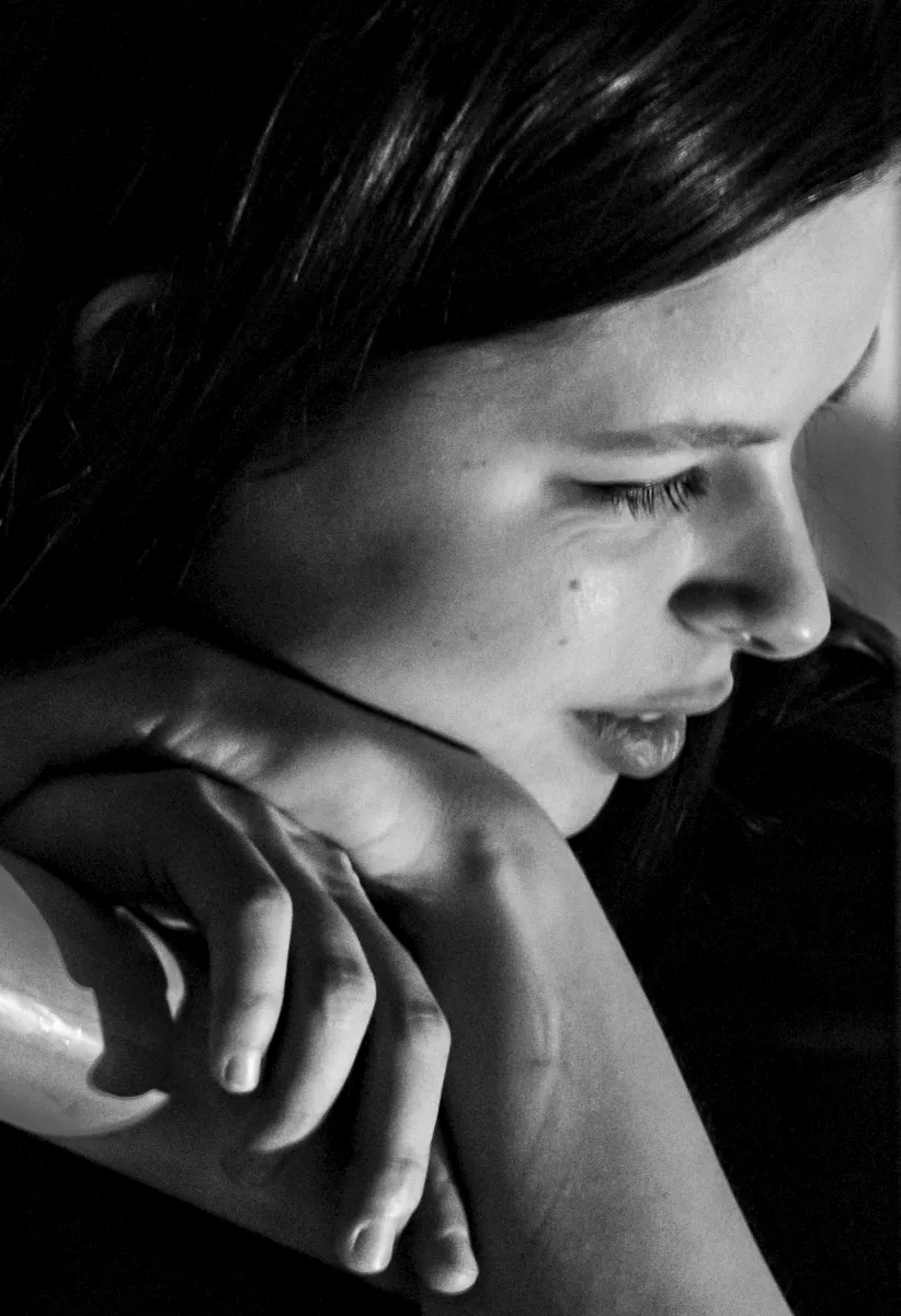 Close-up of a young woman resting her chin on folded arms